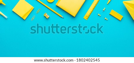 Top view photo of yellow school stationery on turquoise blue background with copy space. Flat lay image of different stationery in order as back to school concept