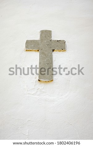 An old religious marble cross embedded in a white wall.