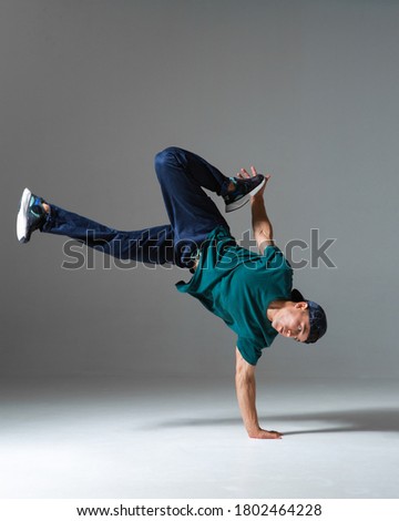 Cool b-boy dancing breakdance on the floor in studio isolated on gray background. Breakdancing school poster