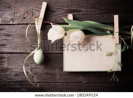 easter egg and paper attach to rope with clothes pins and tulips on wooden background