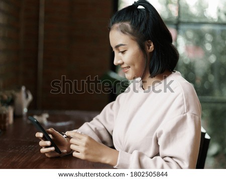 Portrait of an Asian teenage woman chill out and make payment through credit card and smart phone in the cafe. Stock photo.