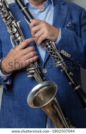 Close-up of male hands holding clarinet and bass clarinet, cropped photo