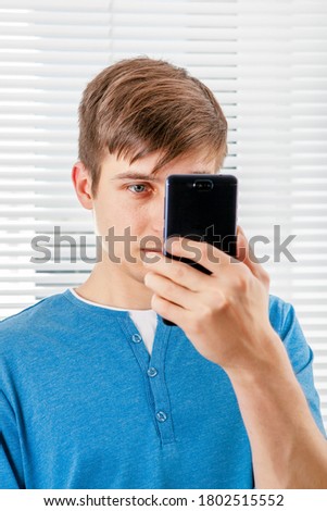 Young Man Take a Picture with a Phone on the Jalousie Background