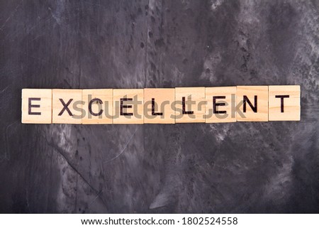 Word excellent made with wooden letters. Grey grunge background.