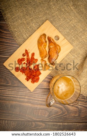 Dried halibut caviar and dried crab meat on a wooden serving Board and a mug of beer on a wooden table. Close up.