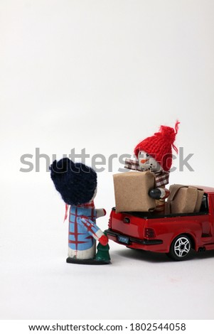 snowmen loading wrapped gifts into red pickup isolated on gray background. Vertical image. Image contains copy space