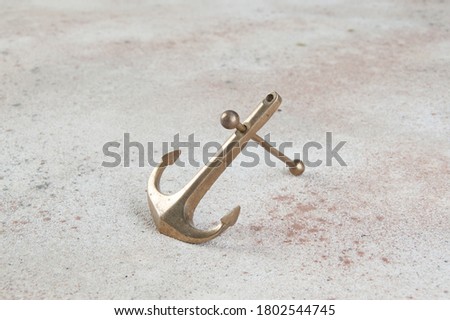Brass anchor on concrete background. Home decor, copy space for text.