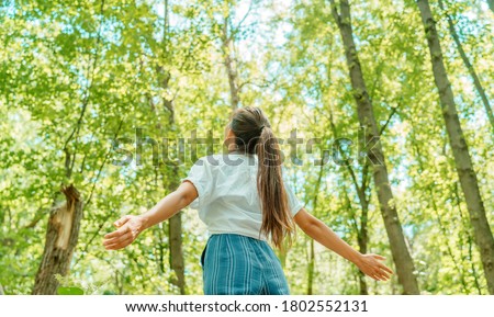 Free woman breathing clean air in nature forest. Happy girl from the back with open arms in happiness. Fresh outdoor woods, wellness healthy lifestyle concept. Royalty-Free Stock Photo #1802552131