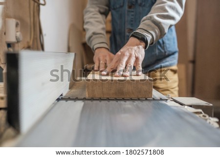 Woodwork and furniture making concept. Carpenter in the workshop processes wood planks on a grinder Royalty-Free Stock Photo #1802571808