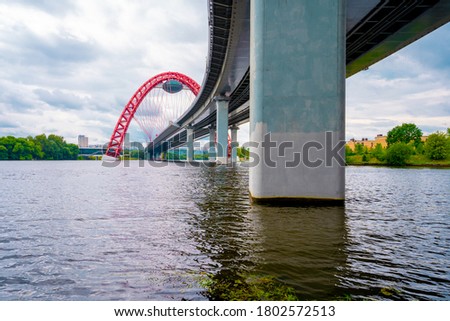 Picturesque red bridge over the river in Moscow, photo taken under the bridge with metal holding beams