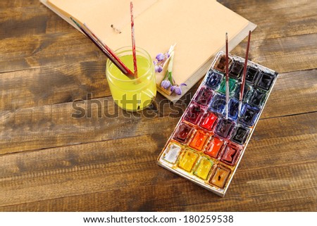 Composition with colorful watercolors, brushes and sketcher on wooden background 