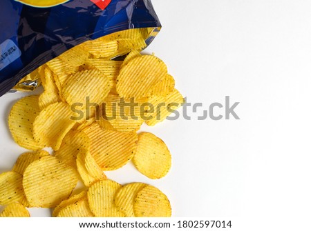 one of the types of snacks, fast food, junk food - ruffled potato chips spilling out of an open bag on a white background   Royalty-Free Stock Photo #1802597014