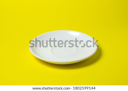 White saucer on a yellow background. An empty pink saucer lies on a yellow surface Royalty-Free Stock Photo #1802599144