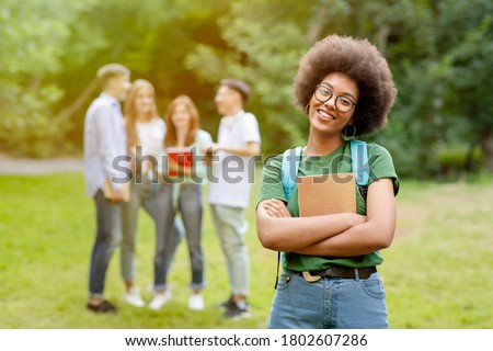 Student Life. Outdoor portrait of smiling black girl posing in front her college friends at campus Royalty-Free Stock Photo #1802607286