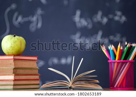 Back to School Concept. Accessories and books against chalkboard.