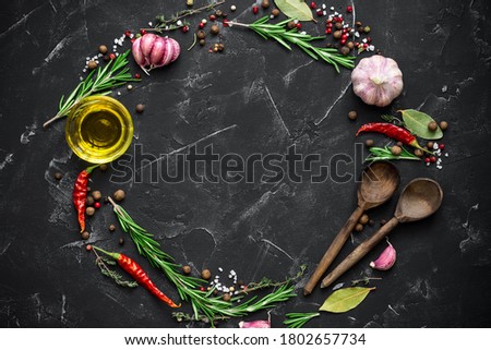 Round frame made of spices, seasonings, vegetables, oil. Black stone culinary background. Top view, flat lay, copy space