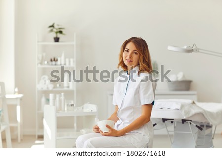 Woman beautician sitting in a beauty salon. Beautician in the white office of the cosmetology clinic. Royalty-Free Stock Photo #1802671618