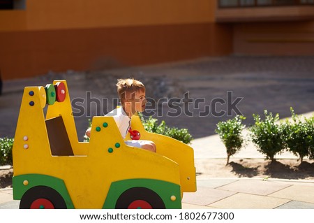 7-year-old boy rides a car in the playground. High quality photo