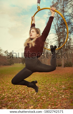 Nice lady posing in autumn park and exercising with steel hoop