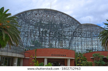 A view of the facade of Yumenoshima Tropical Greenhouse Dome (sign on front translates to "Yumenoshima Tropical Plant Hall") on an cloudy day in summer