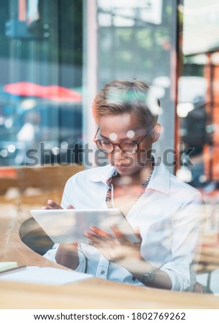 Serious business woman using digital tablet behind large glass window stock photo
