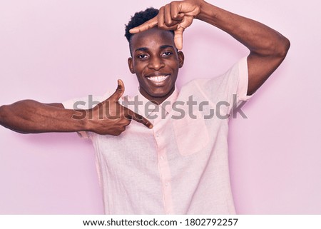 Young african american man wearing casual clothes smiling making frame with hands and fingers with happy face. creativity and photography concept. 