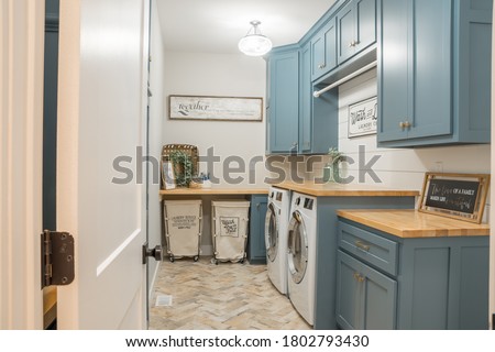 Farmhouse style laundry room, rolling carts, signs, blue cabinets.