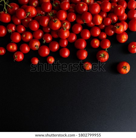 Fresh cherry tomatoes on a black background. Top view with copy space.