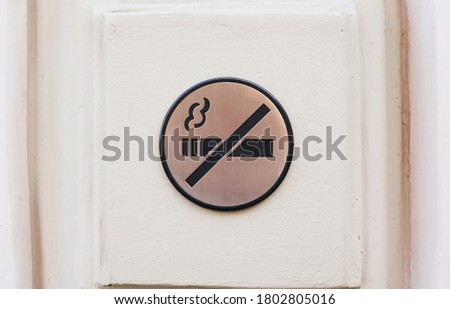 No smoking sign, metallic plate on white wall, toned