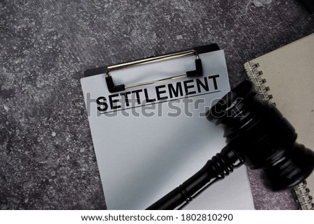 Settlement text write on a paperwork and gavel isolated on office desk.