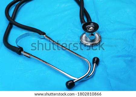 Black Stethoscope and phonendoscope on the blue nonwoven fabric close up. Selective focus. Medical concept. 