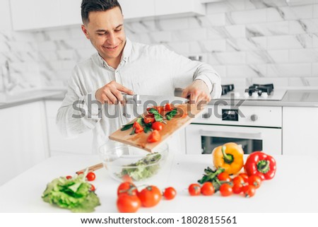 Men preparing salad in white kitchen. Cooking homemade food.