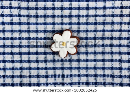 Glazed gingerbread on a towel.
Checkered towel and gingerbread flower.