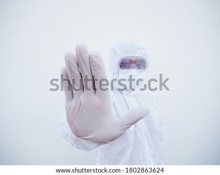 Asian male doctor or scientist in PPE suite uniform showing stop sign while looking ahead. coronavirus or COVID-19 concept isolated white background