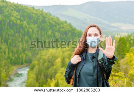 Young woman wearing face mask during coronavirus and flu outbreak showing stop gesture at hike