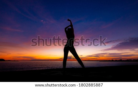 Silhouette woman play aerobic exercise for healthy on beach with twilight sky background.