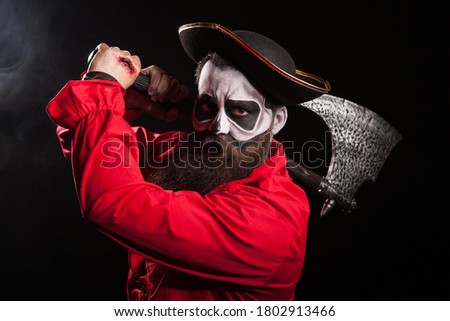 Man dressed up like a pirate for halloween holding and axe over black background.