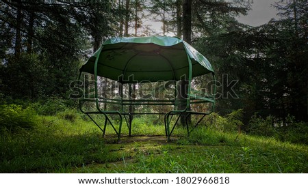 uttarakhand,india-2 june 2020:bench,circular bench in park.this is a picture of a park in forest.bench with roof.green bench structure in a park with roof. Empty park. 