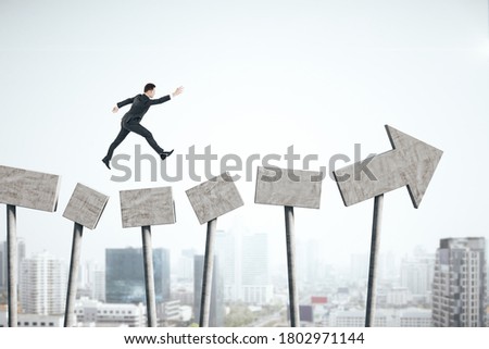 Businessman jumping on gray concrete arrow on city background. Growth and forward concept