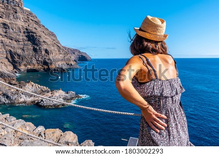 A young woman looking at the cliffs in the town of Poris de Candelaria on the north-west coast of the island of La Palma, Canary Islands. Spain