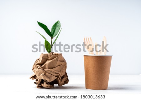 Craft paper coffee cup, green leaves sprout, bark of tree and recycled cutlery top view. Zero waste, eco friendly, natural organic plastic free concept. Earth, biodegradable with copy space. Royalty-Free Stock Photo #1803013633