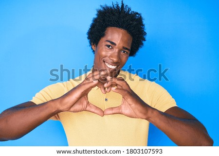 Handsome african american man with afro hair wearing casual clothes smiling in love doing heart symbol shape with hands. romantic concept. 