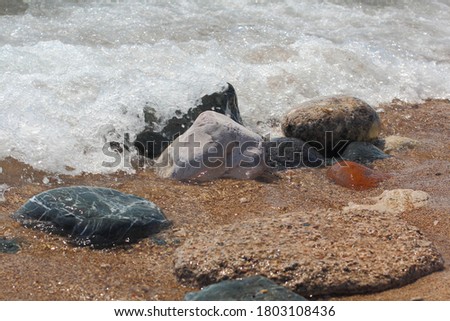 the waves of the sea run up to the shore and beat against the coastal rocks. Beach background photo.