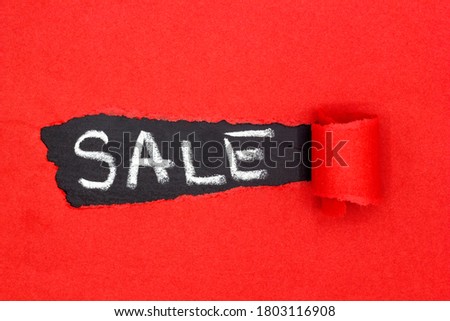 White word SALE on black background on torn red paper. The discount season is open. Time for a sale. Space for text