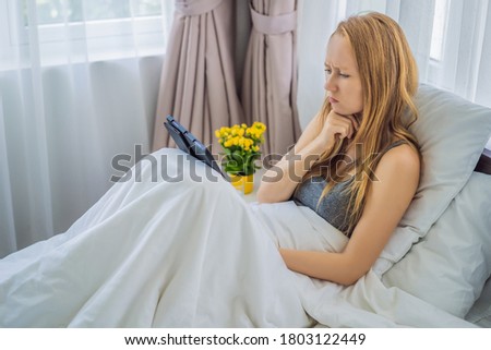 Woman talking by video call while lying in bed
