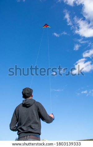 A vertical shot of a male holding a kite in the sky