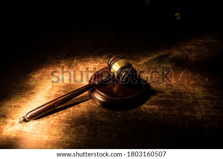 Law, justice concept. Creative artwork table decoration with mallet of the judge on dark foggy background with colorful light. Selective focus
