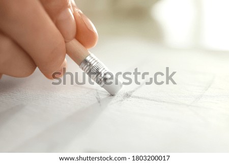 Woman correcting picture on paper with pencil eraser, closeup