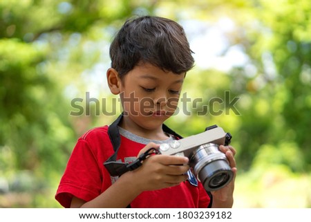 Asian kid use digital camera taking photo in public park