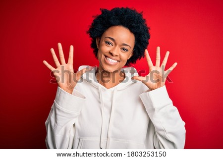 Young beautiful African American afro sportswoman with curly hair wearing sportswear showing and pointing up with fingers number ten while smiling confident and happy.